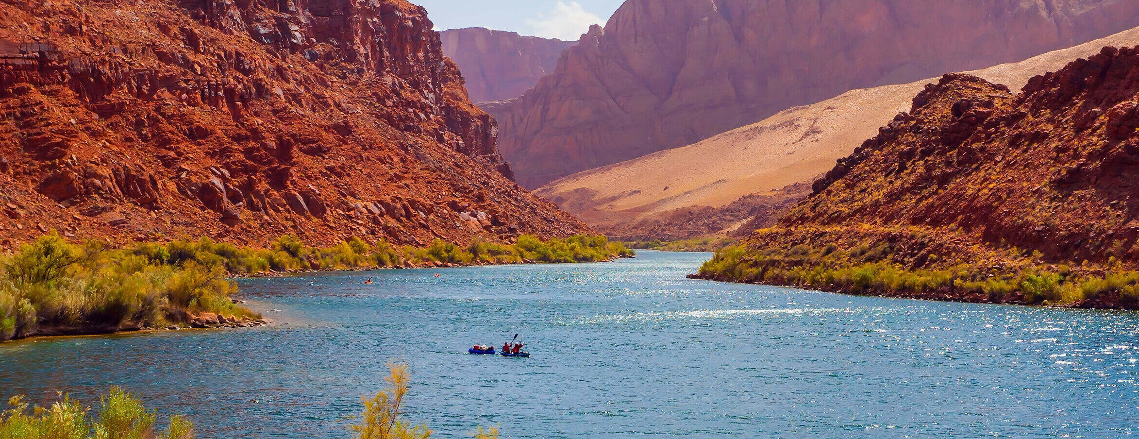 canoes and kayaks on river surrounded by red hills